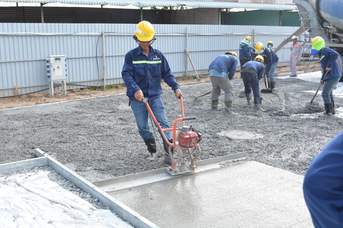 Concreting crew screeding a freshly poured concrete slab